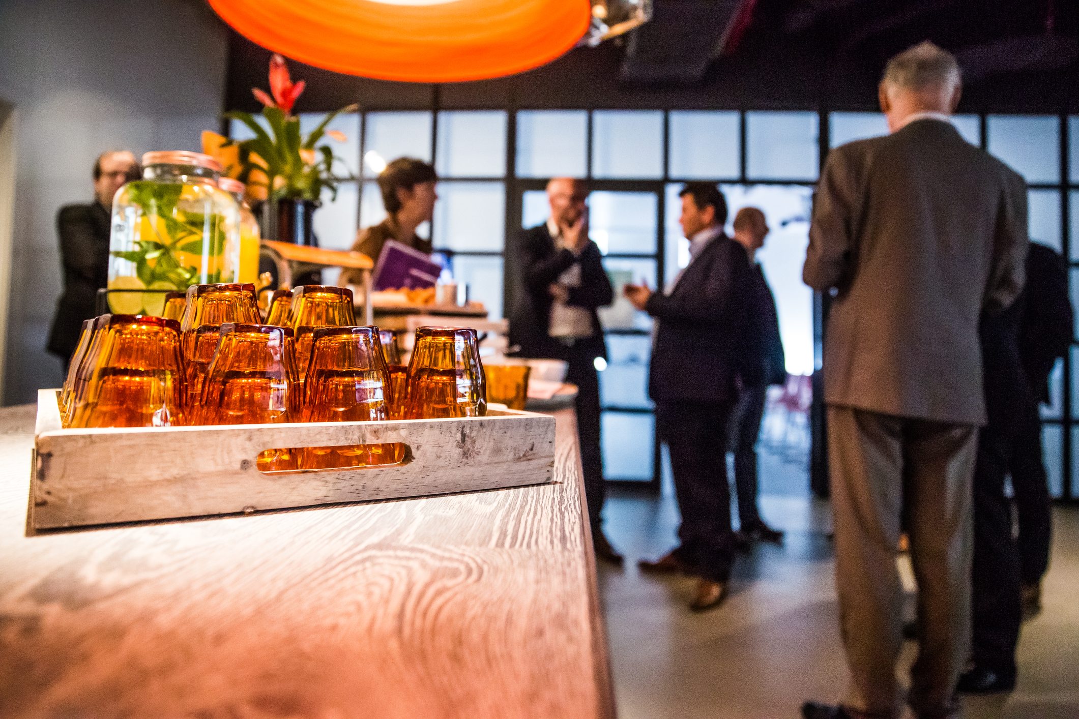 Food waiting to be eaten at a corporate event in a luxury hotel. The table is brown, the plate is lite brown. They are people talking in the background and an orange light on the top of the plate. Business Event Planning - Cultivate Event Planning