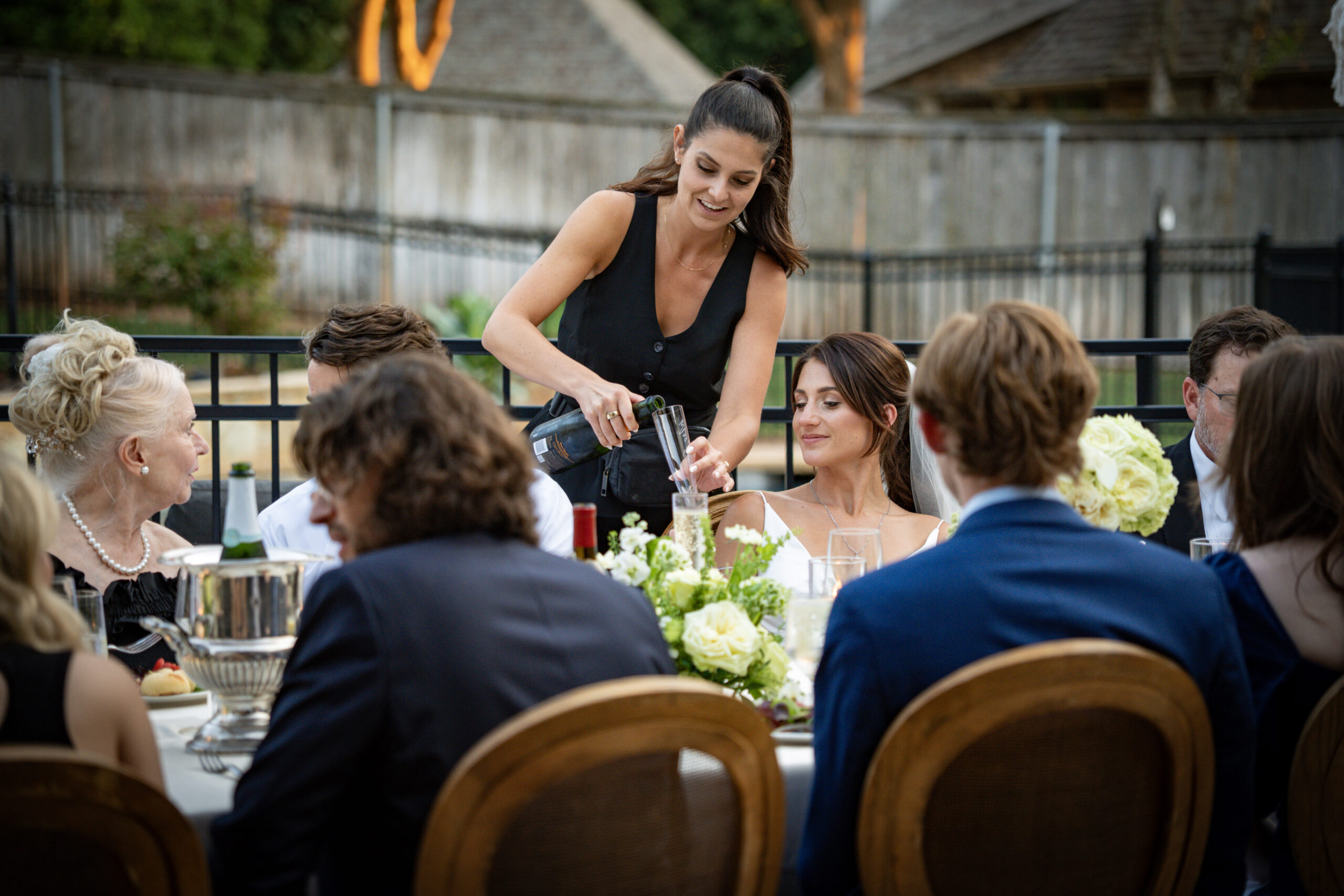 Women in black dress serving champagne at private backyard party. Private Event Planning - Personal Touch - Cultivate Event Planning
