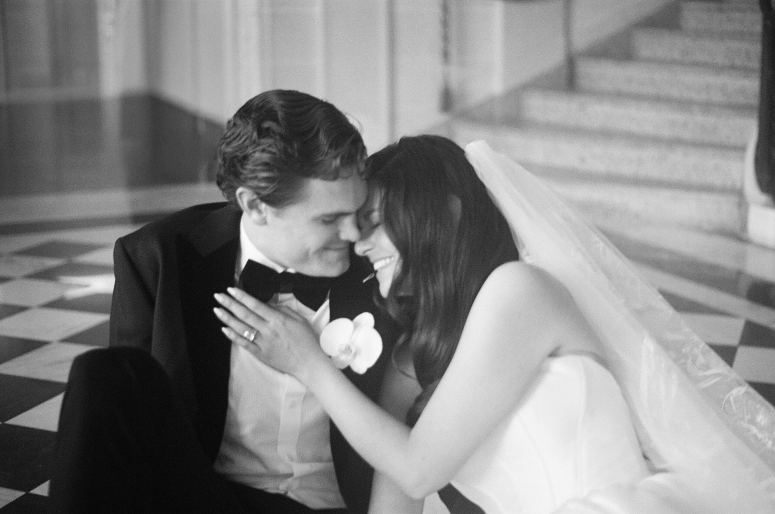 Black and white photo of husband and wife smiling and leaning into each other in the lobby of the hotel.